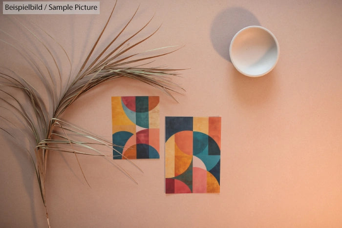 Abstract geometric art pieces on a beige background with a plant stem and circular shadow.