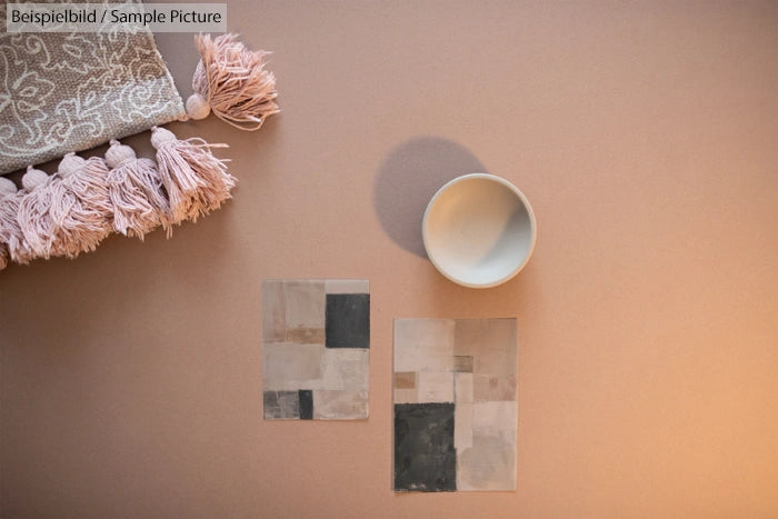 Neutral-toned textiles and ceramics on a beige surface with abstract art pieces.