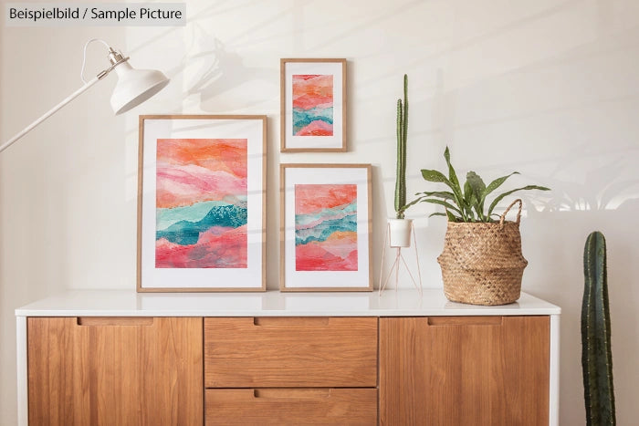 Wooden sideboard with framed abstract art and potted plants on top, in a well-lit modern interior setting.