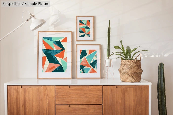 Modern prints with geometric patterns on wooden cabinet in stylish, minimalist room with plants.