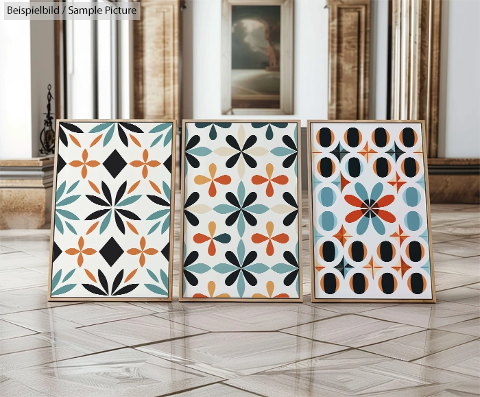 Three framed geometric artworks with vibrant patterns in a gallery setting on a wooden floor.