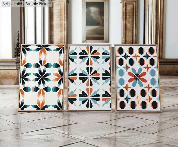 Three abstract geometric art prints with floral patterns in frames on a polished wooden floor in a gallery setting.