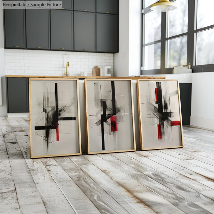 Three abstract paintings with black and red geometric designs set against a modern kitchen backdrop.