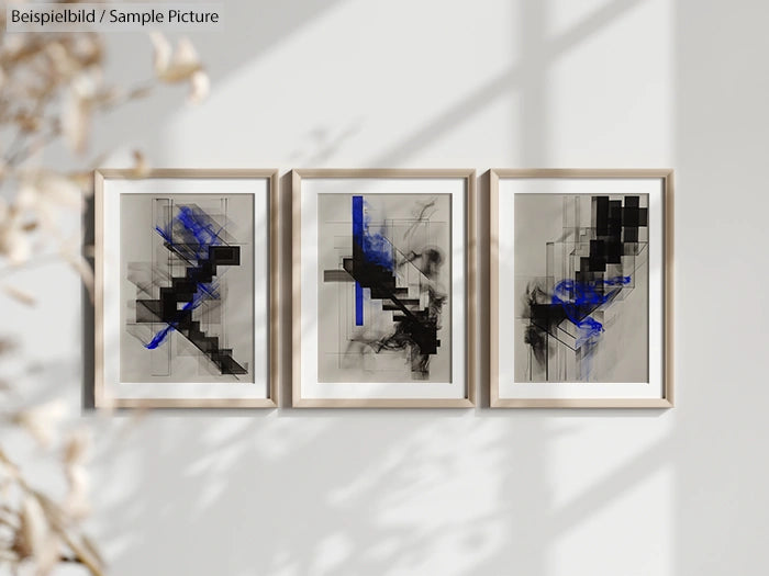 Three abstract paintings with black and blue geometric patterns in white frames on a light-colored wall.