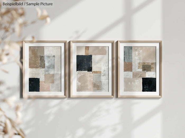 Triptych of abstract geometric paintings with earth tones on a light gray wall, framed with minimal wood frames.