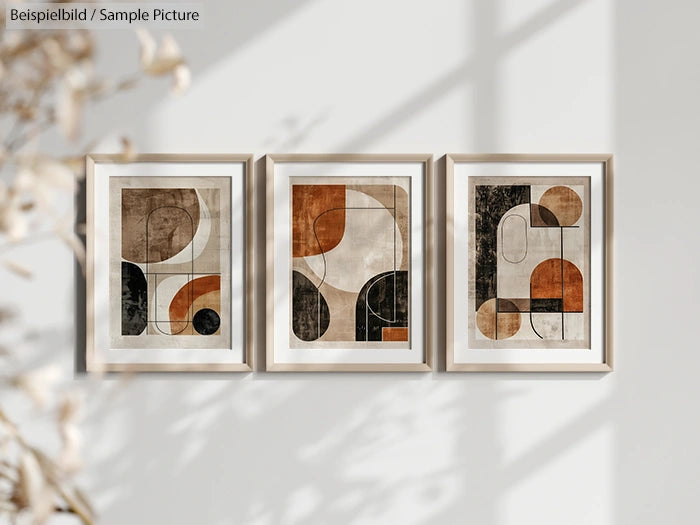 Trio of framed abstract paintings with geometric shapes in earthy tones on a wall.