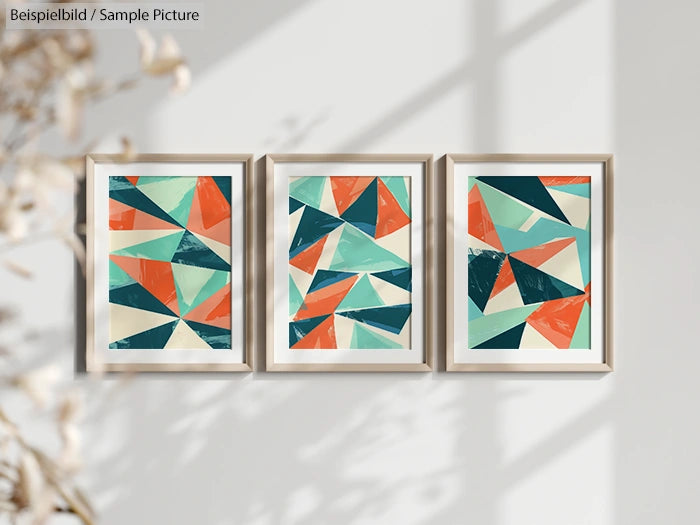 Three framed abstract paintings with geometric shapes in teal, orange, and white, displayed on a sunlit wall.