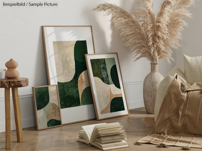 Cozy room featuring framed abstract art with green tones, pampas grass, cushions, and open books on a wooden floor.