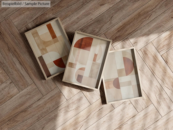 Three framed abstract prints with geometric designs on a wood parquet floor.