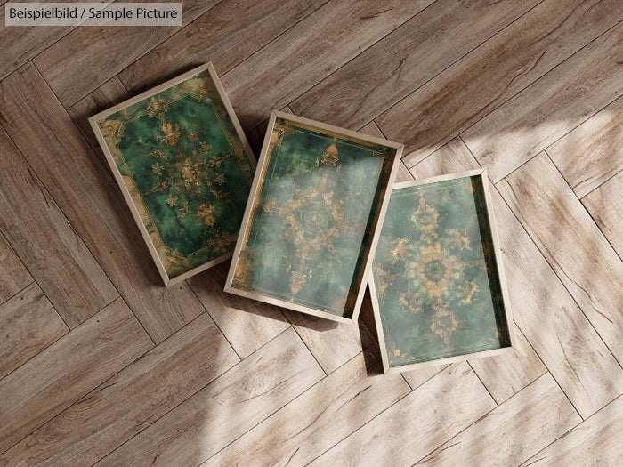 Three green and gold patterned trays on a wooden herringbone floor, lit by sunlight from the right.