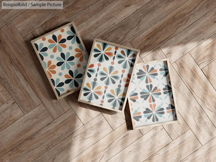 Three framed geometric prints with floral motifs on a wooden floor.