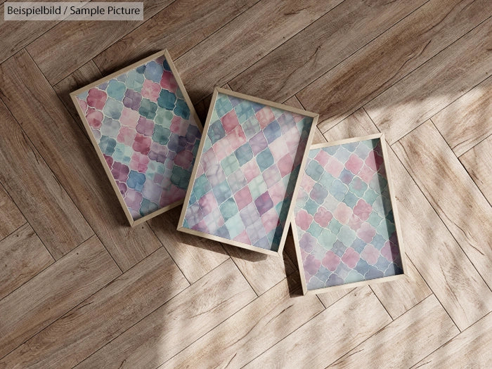 Three framed abstract pastel paintings on wooden floor.