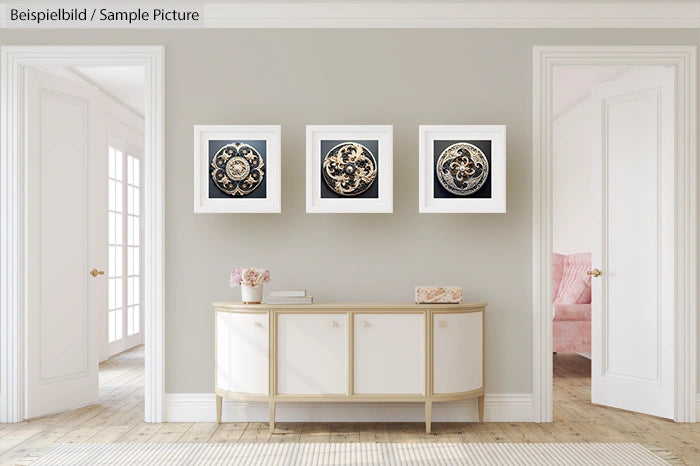 Modern living room with three framed circular art pieces above a white console table, light grey walls, and an armchair.