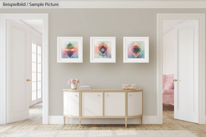 Modern living room with abstract art. White console table under three colorful geometric paintings on a beige wall.