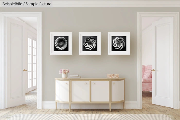 Modern interior with three abstract black and white spiral artworks above a beige console table.