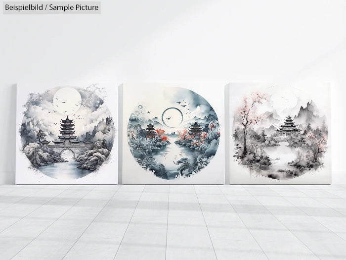 Three ink paintings with pagodas, trees, and circular designs on a white wall.