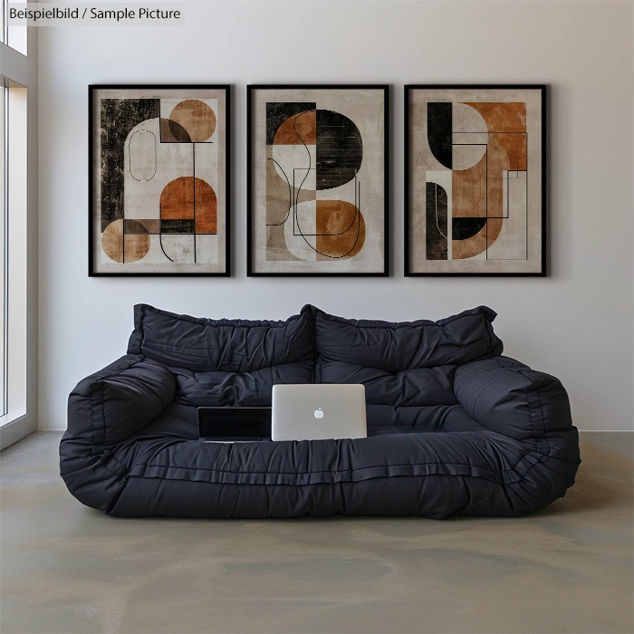 Modern living room with black sofa, laptop, and abstract art on wall.