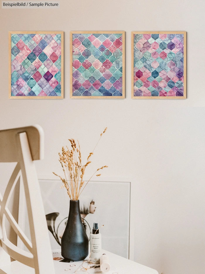 Three abstract watercolor paintings with geometric patterns in pink, blue, and purple hues on a minimalistic wall.