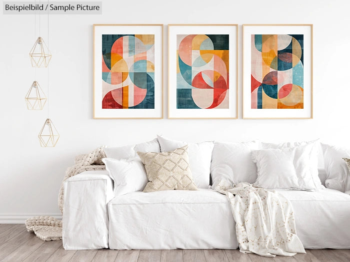 Living room with three abstract geometric art pieces above a white couch and decorative lights on the side.