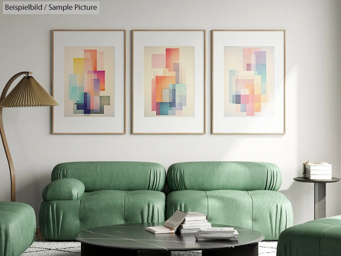 Modern living room with three abstract paintings, green sofas, floor lamp, and coffee table with books.