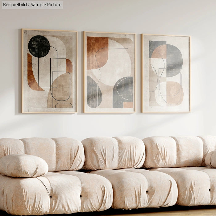 Three abstract geometric art prints above a plush beige sofa in a modern living room setting.