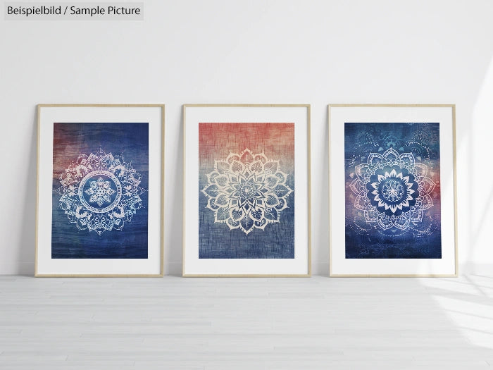 Three framed mandala artworks with blue and red ombre backgrounds displayed against a white wall on wooden floor.