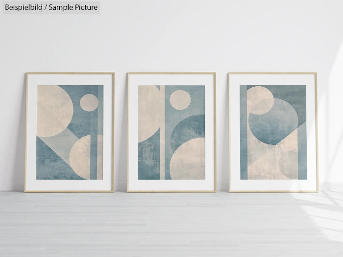 Three framed abstract prints with geometric shapes in blue and beige displayed against a white wall.