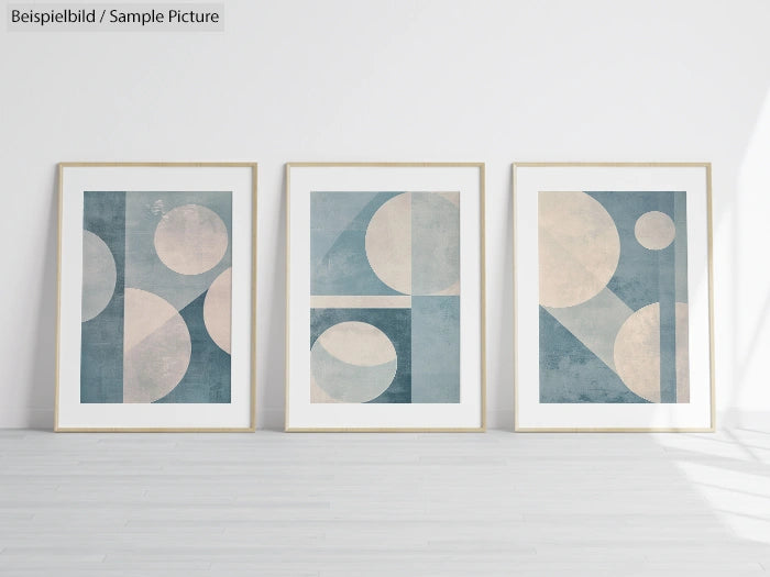 Set of three framed abstract geometric paintings with blue and beige circles and shapes on a white wall background.