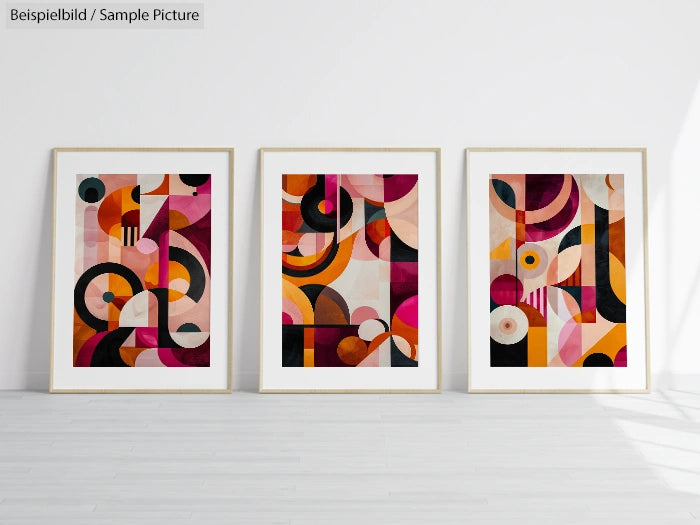 Three abstract geometric paintings with colorful shapes displayed on a white wall.