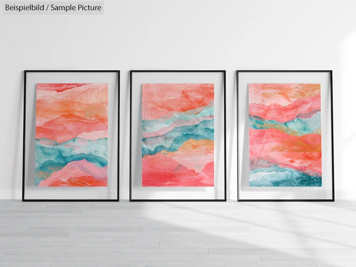 Three abstract paintings with pink, blue, and orange hues in black frames on a white wall.