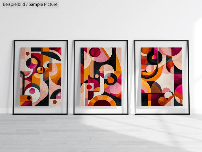 Three framed abstract geometric artworks with circles and arcs in red, pink, orange, and black on a white gallery wall.