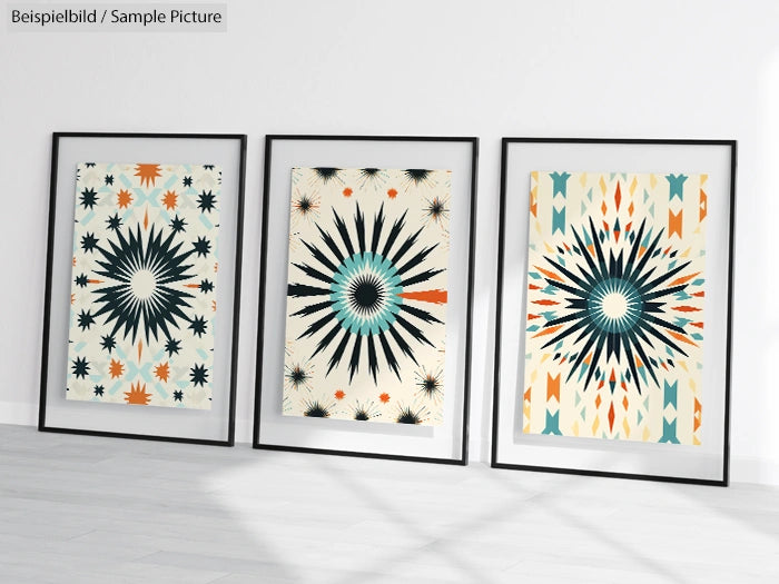 Three framed geometric art prints with black, blue, and orange starburst patterns on a white wall.