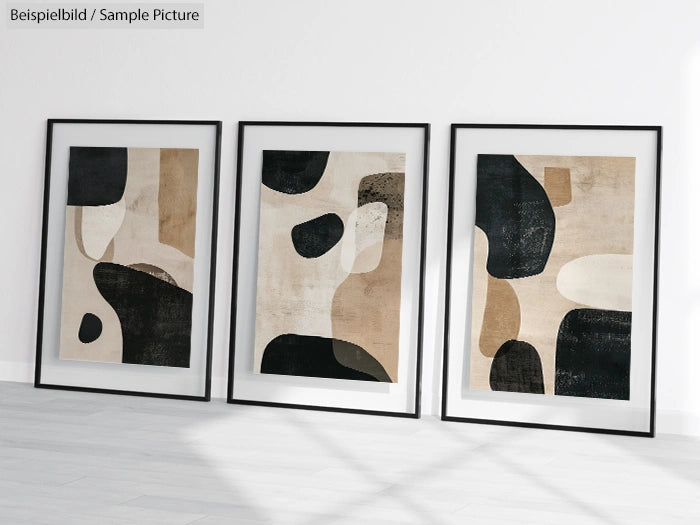 Three framed abstract paintings with black, beige, and white organic shapes on a light gray wall.