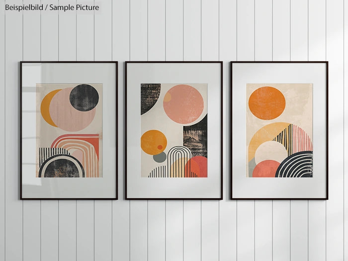 Three framed geometric abstract art prints on a white paneled wall.