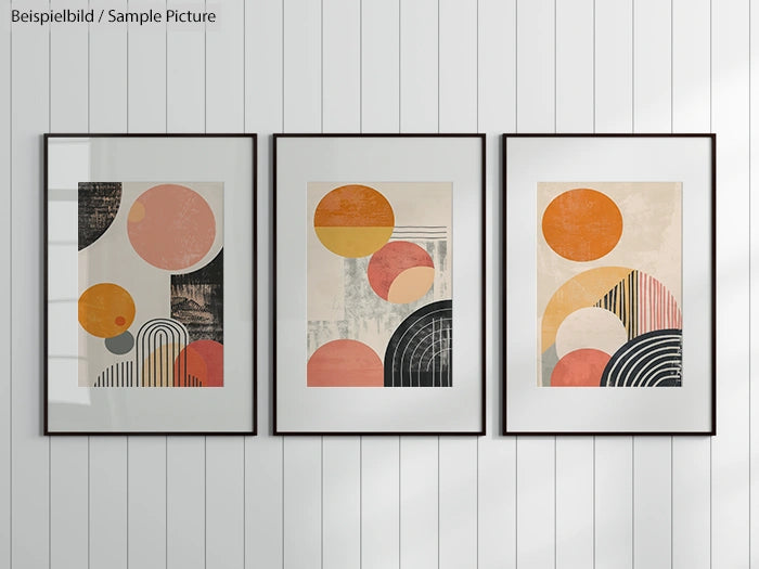 Three framed modern abstract art prints with geometric shapes and muted colors on a white panel wall.