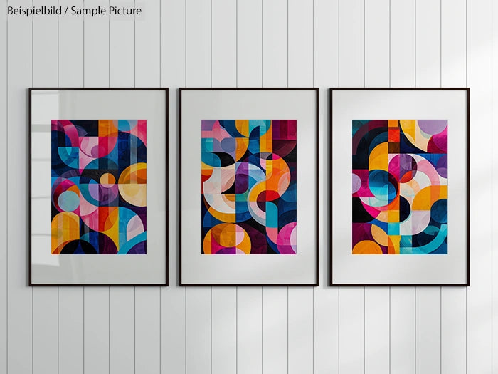 Three framed abstract paintings with colorful geometric shapes on a white paneled wall.