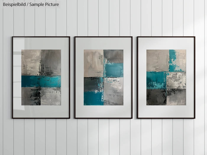 Triptych of abstract paintings with teal, gray, and white geometric patterns in black frames on a white paneled wall.