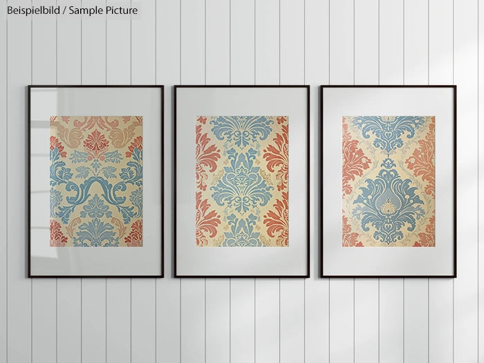 Three framed artworks with ornate damask patterns in blue and red hues on a white wall.