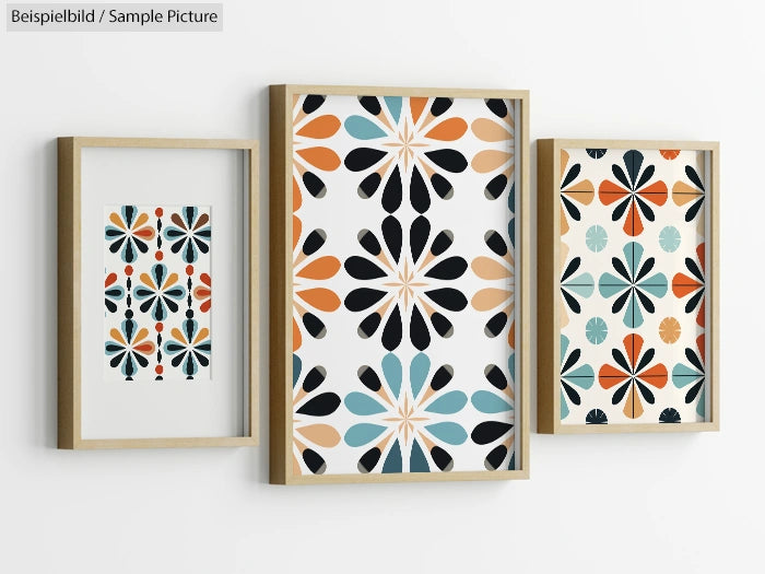 Three framed abstract art prints with floral-like patterns in black, orange, and teal on a white background.