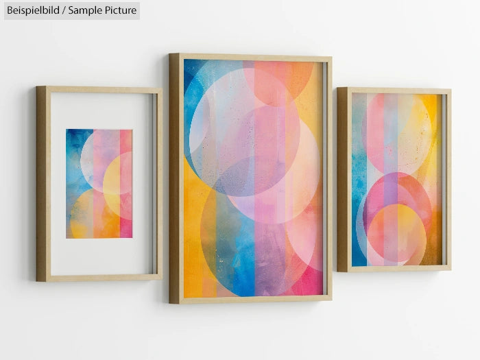 Three framed abstract paintings with colorful circles and gradients on a white wall.