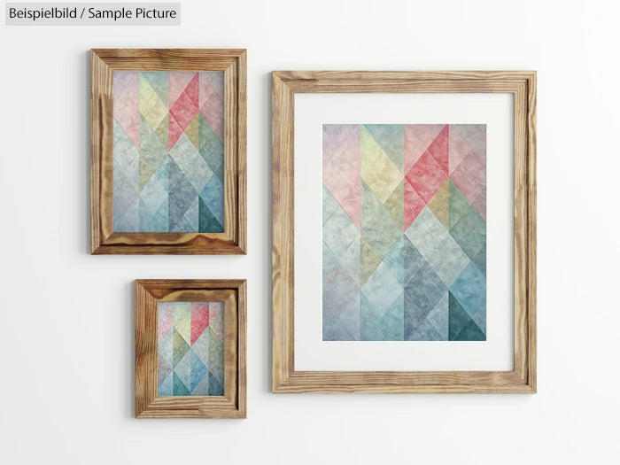 Three wooden-framed geometric prints on a white wall, each showcasing pastel triangles in various sizes.