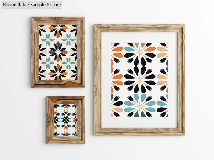 Three framed artworks with geometric floral patterns in black, orange, and teal on a white wall.