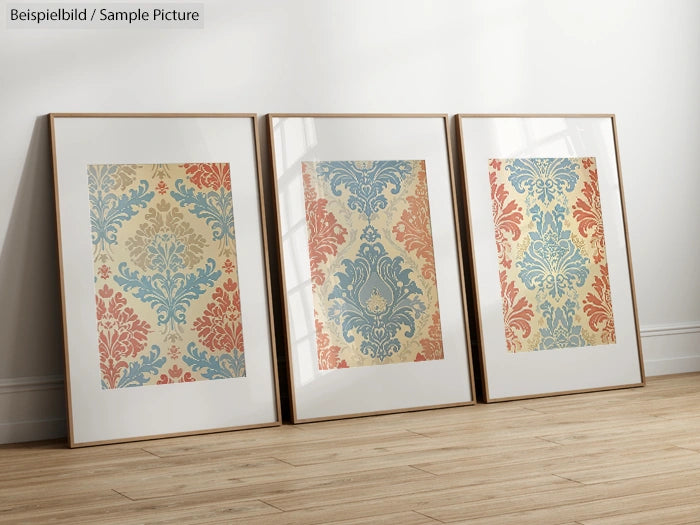 Three framed wall art pieces with vintage floral patterns in red, blue, and beige tones on a wooden floor.