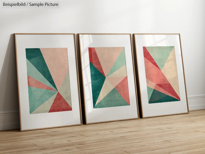 Three framed geometric abstract artworks on a wooden floor against a white wall.