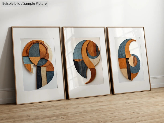 Three framed abstract artworks with geometric shapes in blue, orange, and beige tones on a wooden floor.